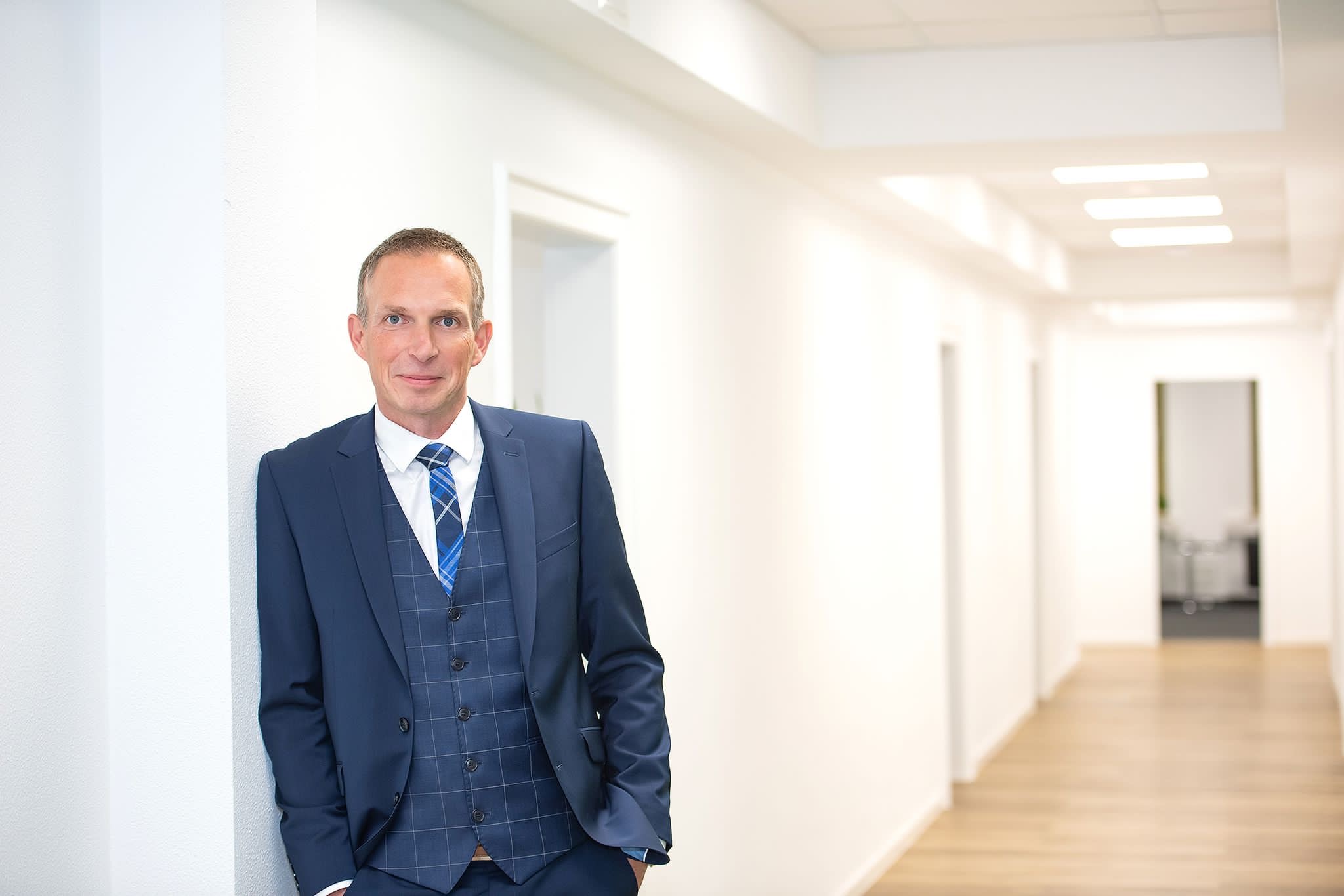 Rechtsanwalt Scharrmann im Anzug in einem Flur